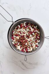 Mixed dried beans in a metal strainer for healthy eating, plant-based protein, and fiber source.