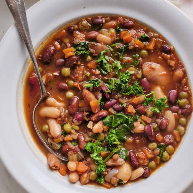 Hearty vegan bean and vegetable soup with colorful ingredients, fresh herbs, and nutritious appeal for healthy eating and plant-based meal ideas.
