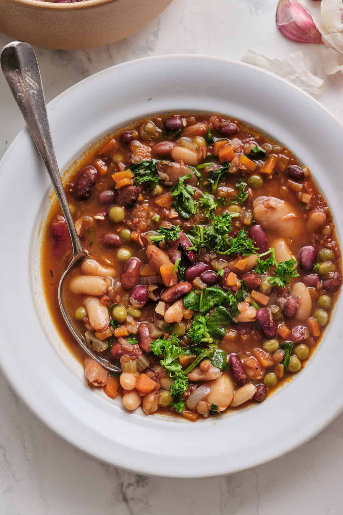 Hearty vegan bean and vegetable soup with colorful ingredients, fresh herbs, and nutritious appeal for healthy eating and plant-based meal ideas.
