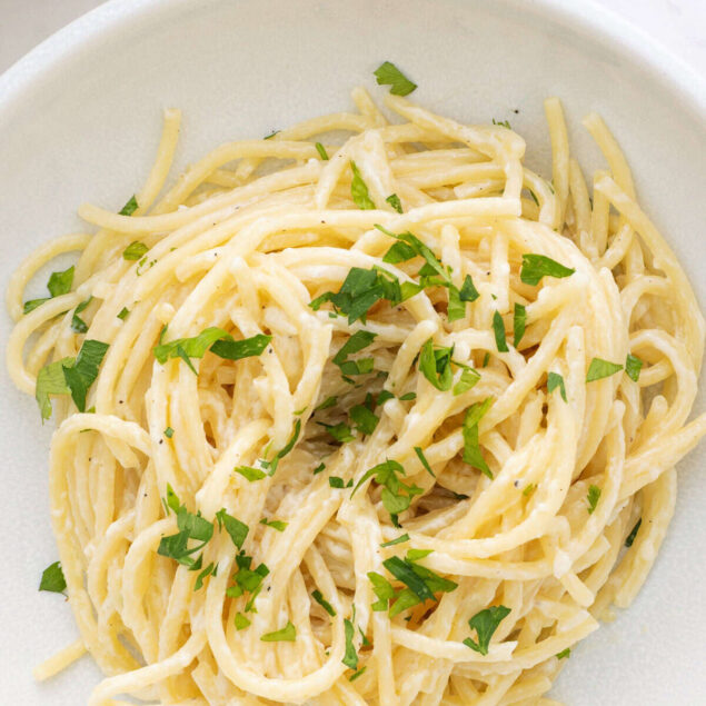 Creamy vegan Alfredo pasta with garlic, herbs, and plant-based sauce on a white plate. Perfect for healthy, gluten-free, and dairy-free meal options from Food Faith Fitness.