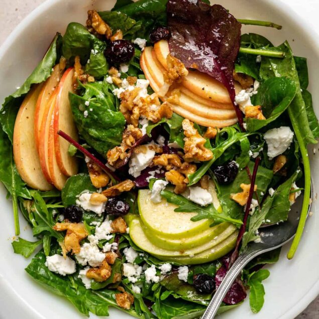 Fresh healthy vegetable salad with apples, blueberries, walnuts, crumbled cheese, and mixed greens, perfect for nutritious eating and fitness diets.