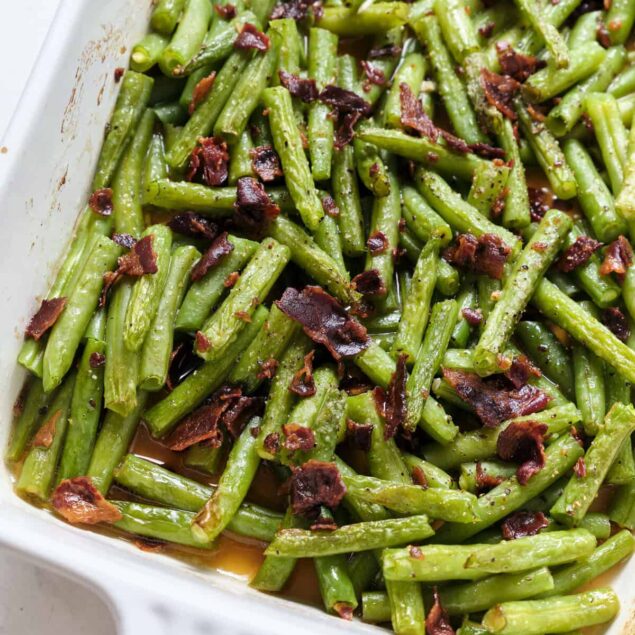Roasted green beans with crispy bacon bits in a white casserole dish, healthy and flavorful side dish, perfect for nutritious family meals.