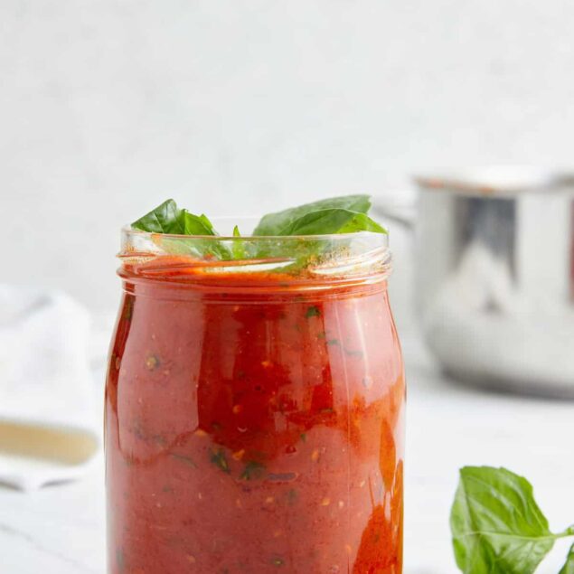 Vegan marinara sauce with fresh basil in a glass jar, healthy homemade Italian tomato sauce perfect for a nutritious meal.