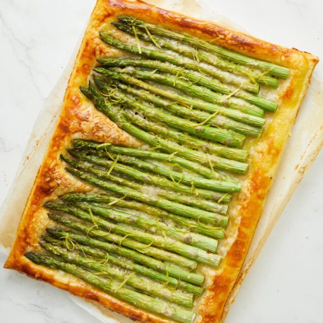 Roasted asparagus sheet pan pizza with cheese, on a white marble background, health-conscious, vegetarian meal.