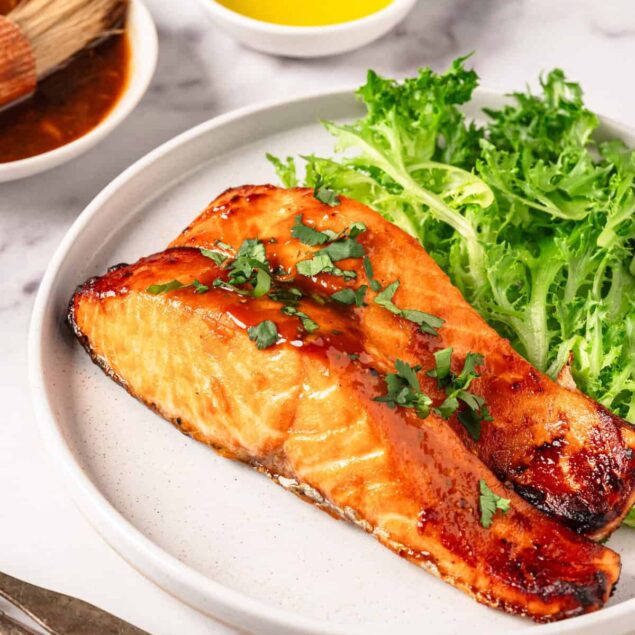 Baked salmon with fresh greens and a side of olive oil, promoting healthy eating and balanced nutrition.