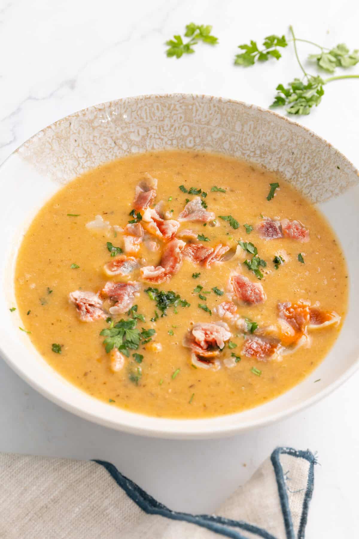 Creamy bacon and potato soup garnished with fresh herbs, perfect for a healthy meal on Food Faith Fitness recipes.