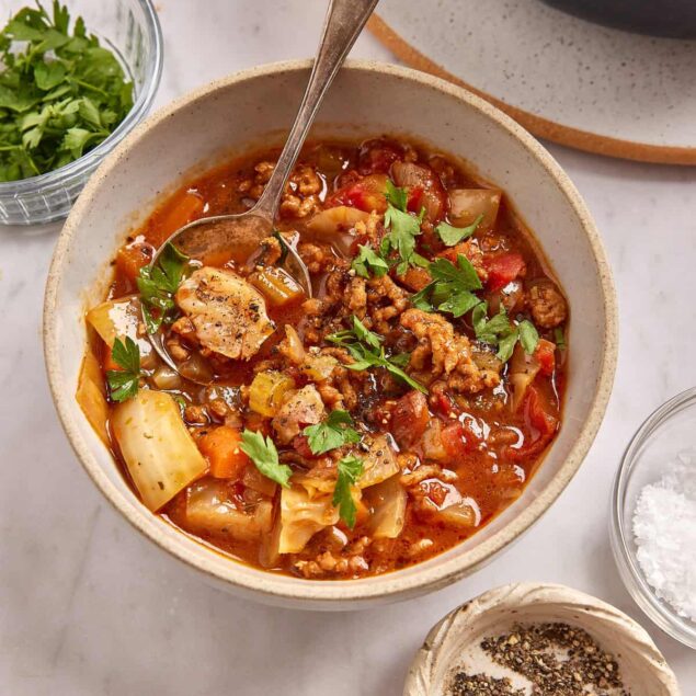 Hearty homemade beef and vegetable soup in a rustic bowl garnished with fresh herbs, offering a nutritious and comforting meal perfect for meal prep or cozy family dinners.