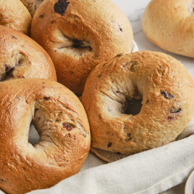 Soft blueberry bagels on a white cloth with fresh blueberries, ideal for healthy breakfast recipes and nutritious food choices.