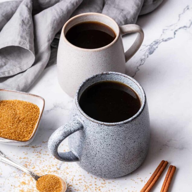 Rich black coffee in modern ceramic cups on marble surface, with cinnamon sticks and brown sugar, healthy coffee beverage, food faith fitness nutrition, morning energy boost.