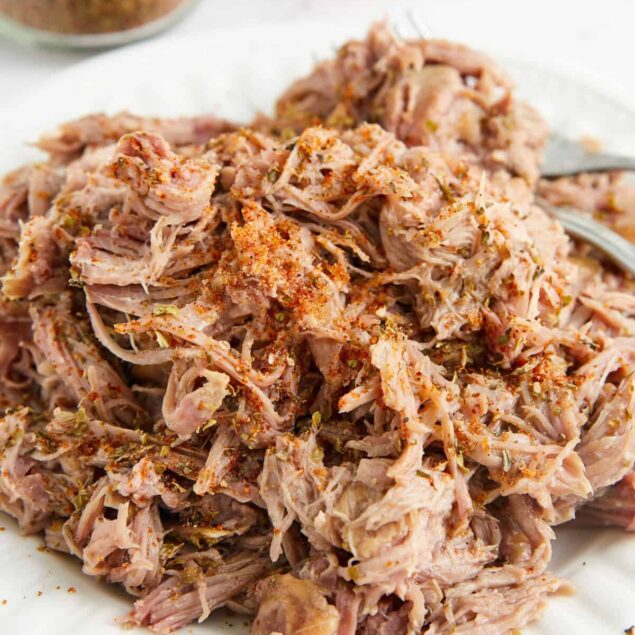 Slow cooker shredded chicken with herbs and spices, perfect for healthy meal prep and versatile recipes.