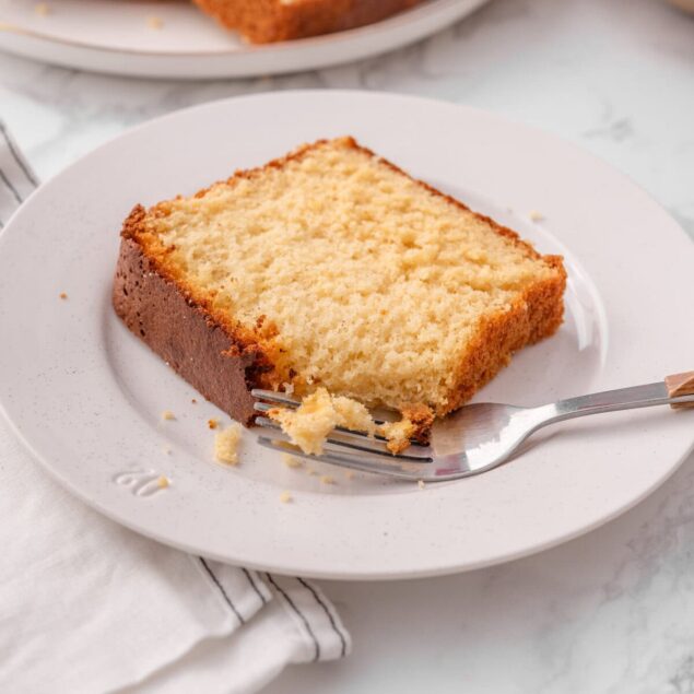 Fluffy homemade vanilla sponge cake served on a white plate with a fork, perfect for healthy dessert recipes from Food Faith Fitness.