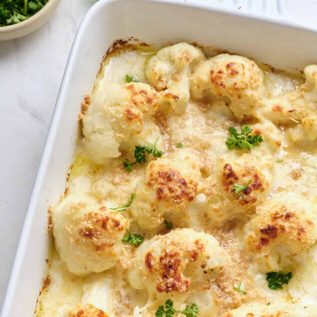 Creamy baked cauliflower gratin with melted cheese and fresh parsley, a healthy and delicious low-carb vegetable casserole recipe from Food Faith Fitness.