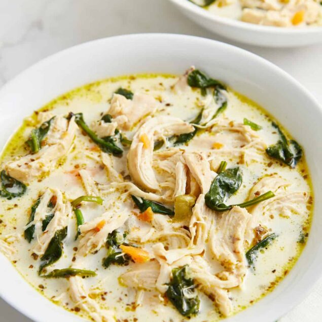 Creamy chicken and spinach soup with herbs in a white bowl, healthy and flavorful recipe, perfect for meal prep and nutritious eating.