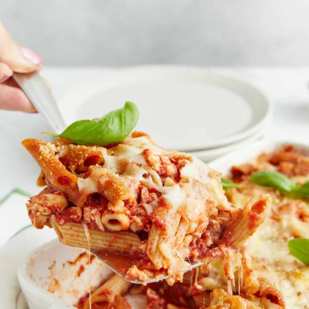 Savory baked ziti pasta dish with melted cheese and fresh basil garnish, perfect for healthy eating and meal prep. Delicious comfort food with nutritious ingredients from Food Faith Fitness.