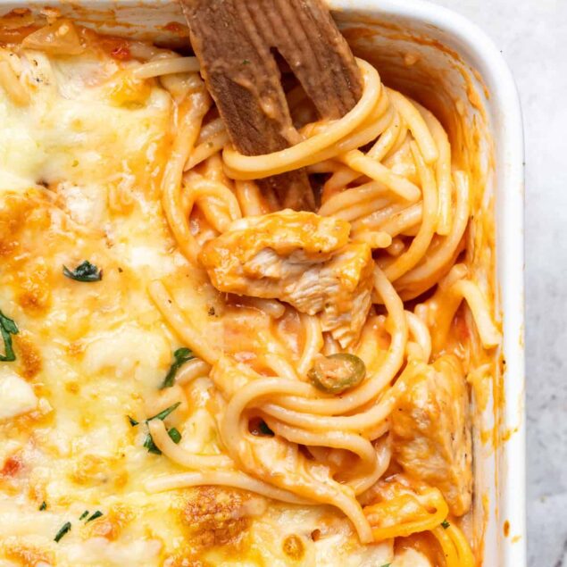 Creamy chicken and spaghetti casserole with melted cheese, topped with fresh herbs, served in a white baking dish. Perfect comfort food for a healthy, delicious meal.
