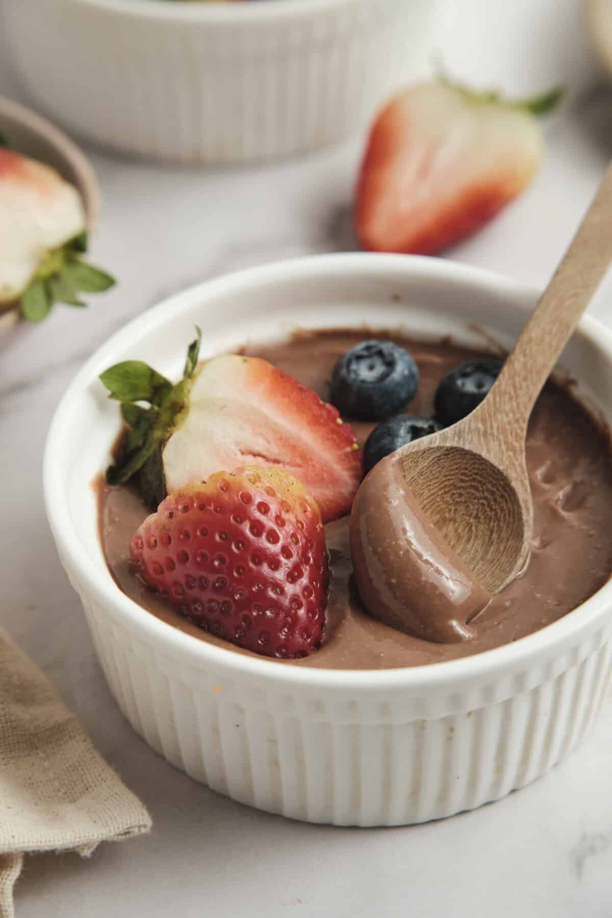 Rich chocolate avocado pudding with fresh strawberries and blueberries, healthy dessert recipe, dairy-free, plant-based snack, low-sugar indulgence, food faith fitness recipe.