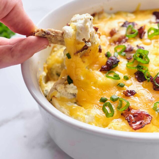 Creamy cheesy chicken casserole topped with bacon and green onions, served in a white dish, perfect for healthy comfort food meals and meal prep.