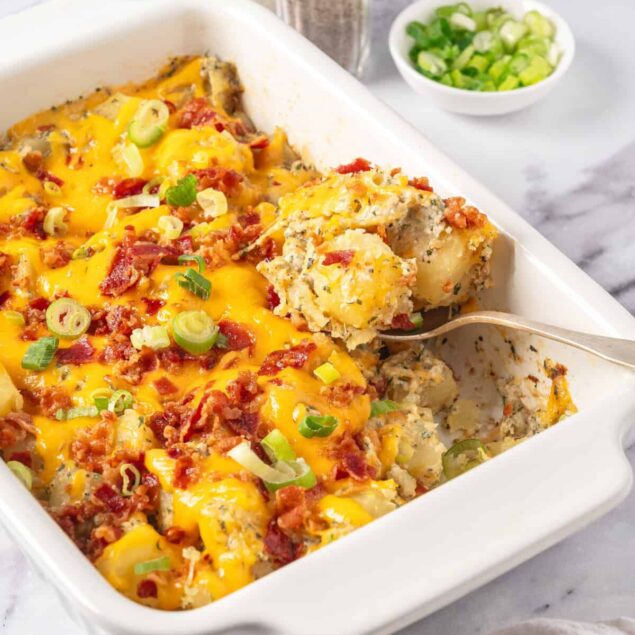Creamy cauliflower broccoli casserole baked with cheese, bacon, and green onions in a white baking dish. Perfect healthy comfort food recipe for meal prep or family dinners.