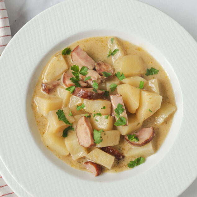 Creamy potato and bacon stew garnished with fresh parsley, served in a white bowl for a comforting and healthy meal. Perfect for clean eating and nutritious weight loss recipes.