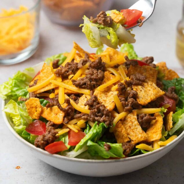 Crunchy taco salad with ground beef, shredded cheese, lettuce, tomatoes, and crispy tortilla chips, perfect for healthy eating and meal prep. A delicious, nutritious taco bowl option from Food Faith Fitness.
