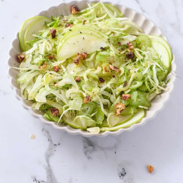 Fresh green cabbage and fennel salad with apple slices, walnuts, and herbs, perfect for healthy eating and meal prep.