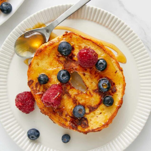 Fluffy French toast topped with fresh berries and drizzled with syrup, healthy breakfast idea from Food Faith Fitness. Perfect for a nutritious morning meal.