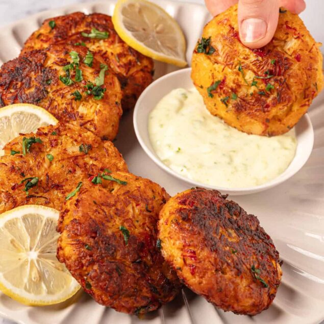 Juicy Indian chicken tikka meatballs with lemon and cilantro, served with creamy yogurt sauce on a white plate.