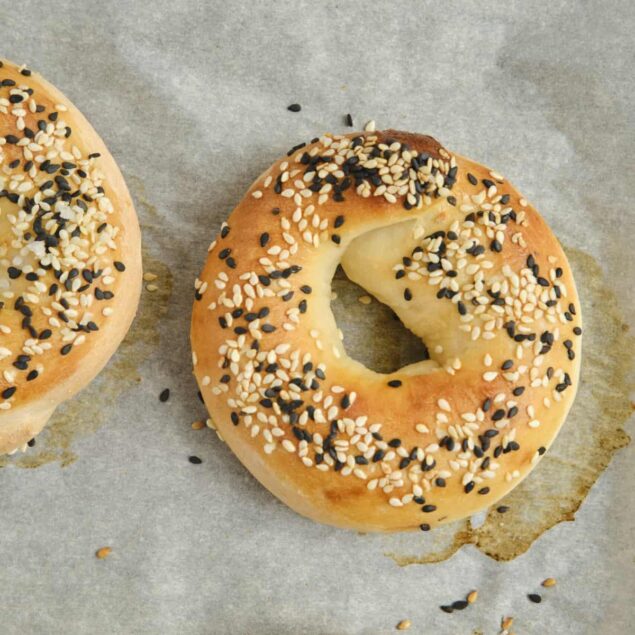 Soft bagels topped with white and black sesame seeds on baking sheet, healthy breakfast options from Food Faith Fitness.