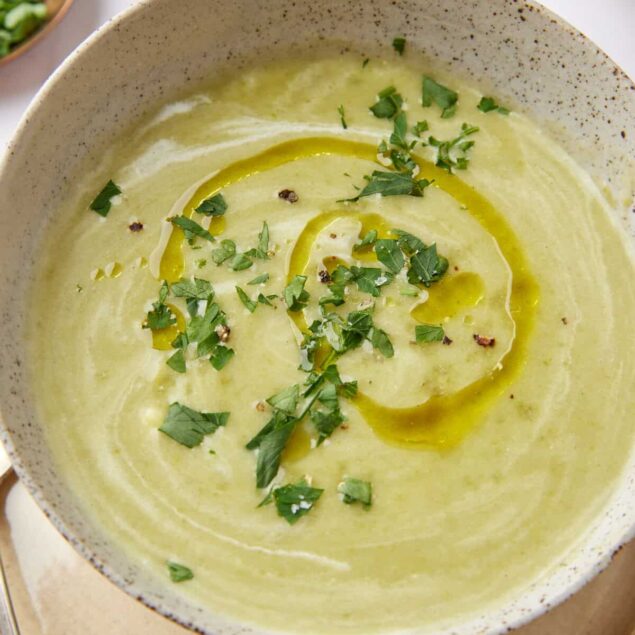 Creamy green vegetable soup garnished with chopped herbs and drizzled with olive oil, served in a rustic bowl for healthy eating and wholesome recipes.