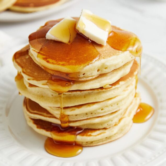 Fluffy stack of healthy pancakes drizzled with maple syrup and topped with butter, ideal for nutritious breakfast recipes on Food Faith Fitness.