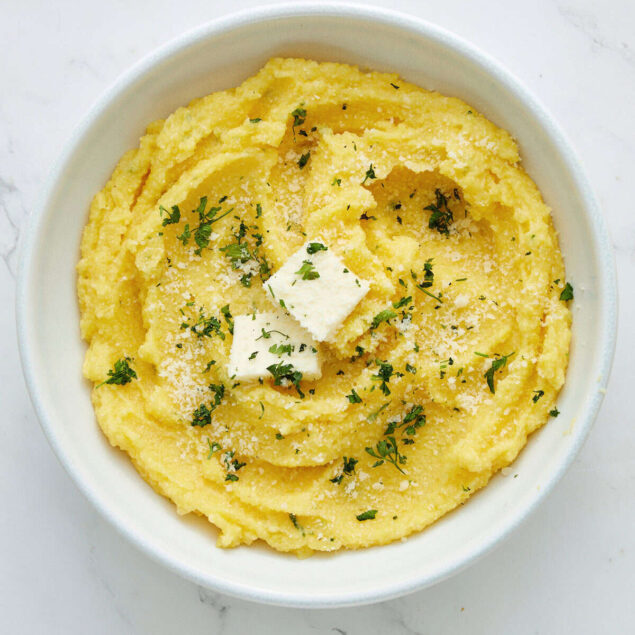 Creamy lemon garlic mashed potatoes with herbs and parmesan cheese in a white bowl.
