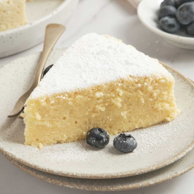 Delicious lemon blueberry cheesecake slice with powdered sugar, fresh blueberries, and a light, creamy texture, perfect for healthy dessert options from Food Faith Fitness.
