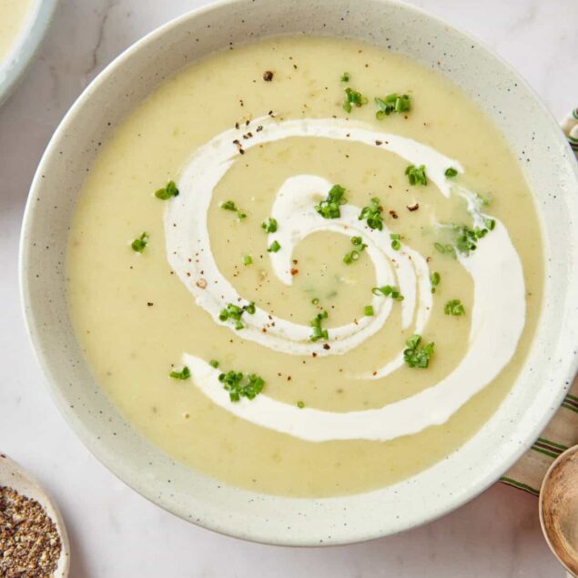 Creamy vegan potato leek soup garnished with chopped green onions and a swirl of dairy-free cream, perfect for healthy comfort food recipes.