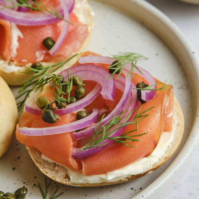 Fresh smoked salmon appetizers topped with red onion, dill, and capers on toasted bread slices. Perfect healthy snack or light meal idea from Food Faith Fitness.