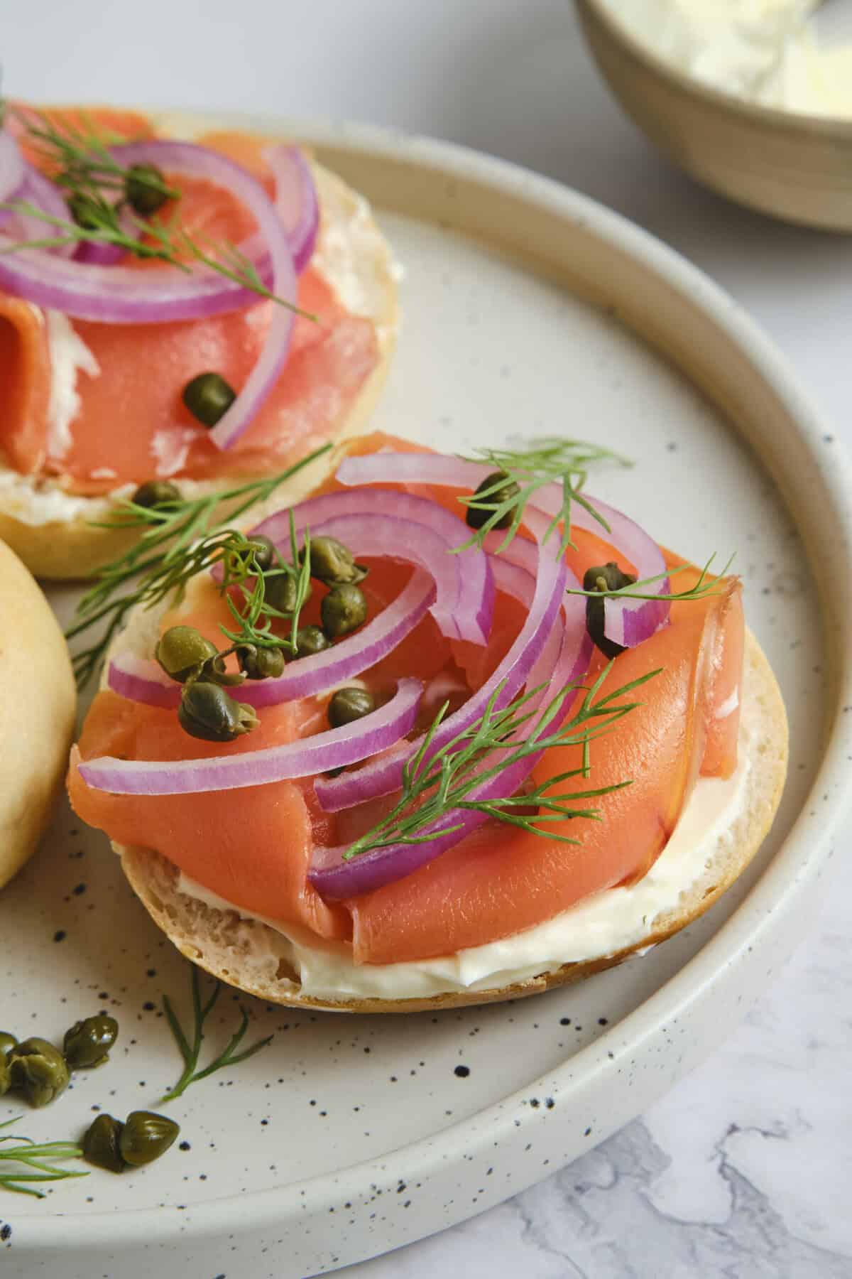 Fresh smoked salmon appetizers topped with red onion, dill, and capers on toasted bread slices. Perfect healthy snack or light meal idea from Food Faith Fitness.