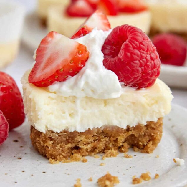 Butterscotch Berry Cheesecake Bars topped with fresh strawberries, raspberries, and whipped cream, perfect for healthy dessert options and fruit-loving recipes.