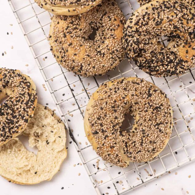 Golden bagels topped with sesame and poppy seeds on a cooling rack, fresh from the oven, perfect for healthy breakfast or snack options.