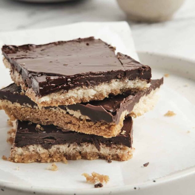 Rich chocolate layered dessert bars with a crunchy coconut and nut base, topped with glossy chocolate ganache, perfect for healthy snack inspiration and gluten-free sweet recipes.
