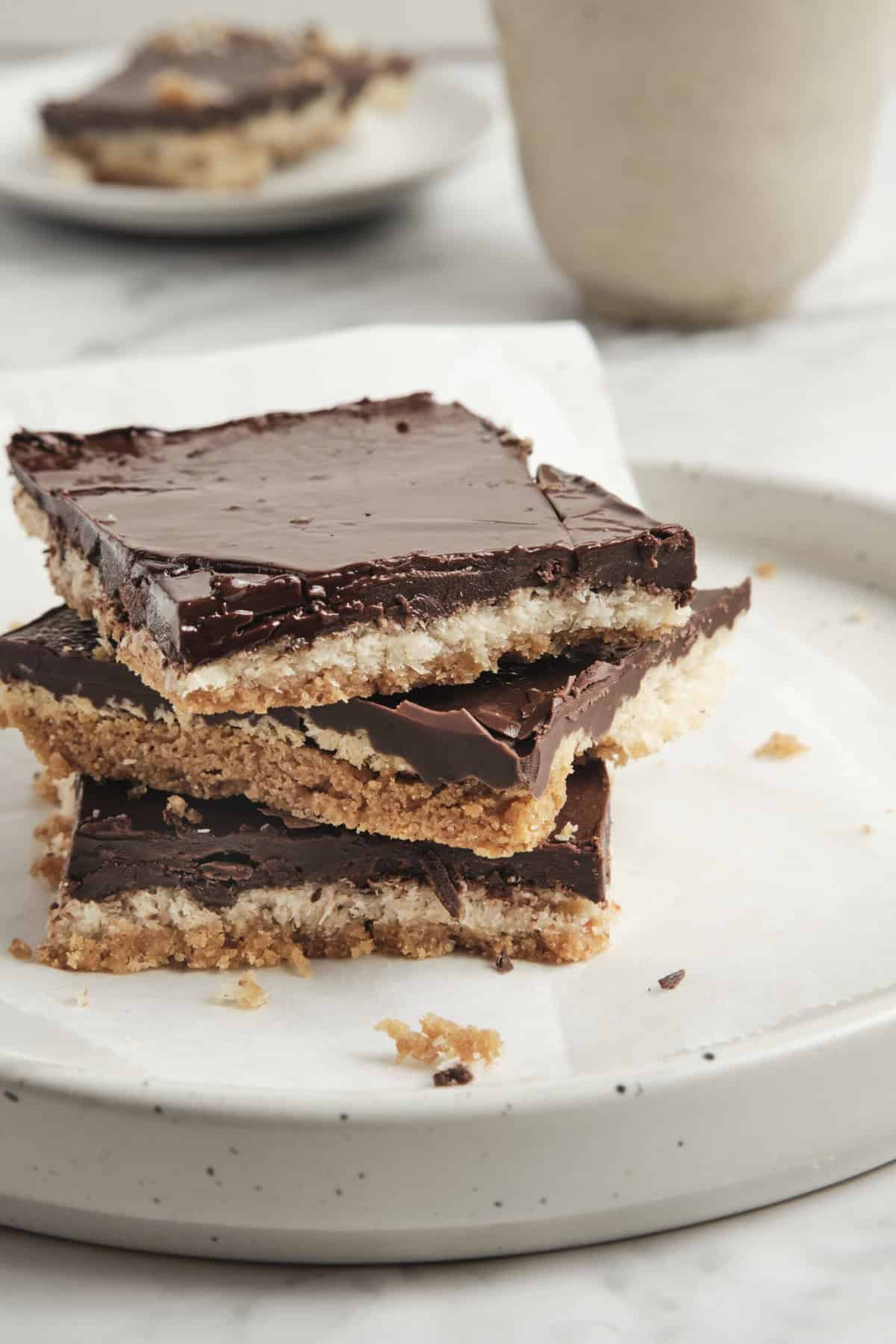 Rich chocolate layered dessert bars with a crunchy coconut and nut base, topped with glossy chocolate ganache, perfect for healthy snack inspiration and gluten-free sweet recipes.