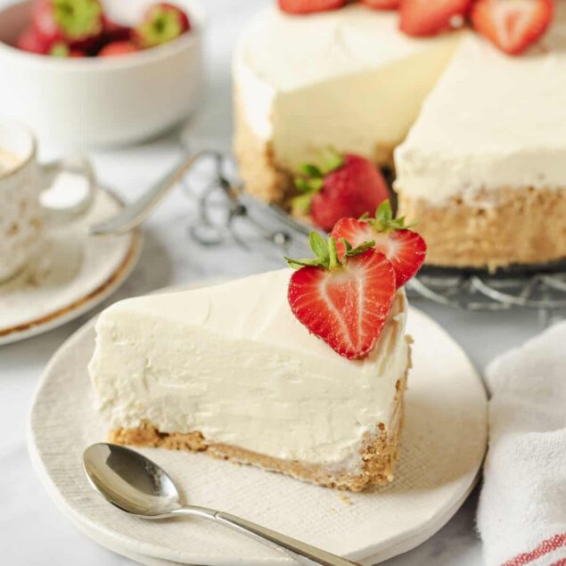 Delicious homemade strawberry cheesecake with fresh strawberries on top, served on a white plate, highlighting healthy dessert options on Food Faith Fitness.