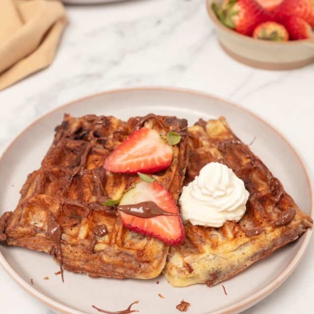 Crispy French toast topped with strawberries and whipped cream on a white plate, healthy breakfast recipe, food faith fitness.