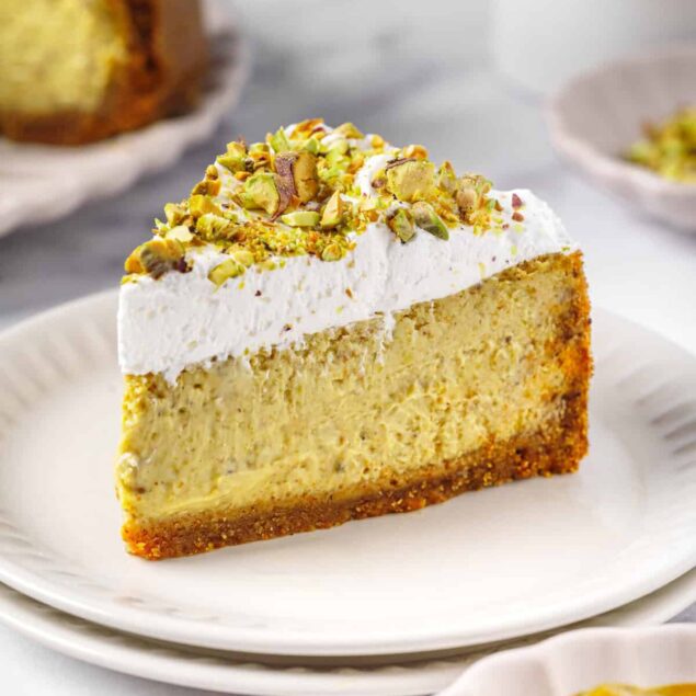 Creamy lemon cheesecake topped with chopped pistachios on a white plate, featuring a crumbly crust and smooth filling. Perfect for health-conscious dessert lovers seeking light, nutritious, and delicious recipes.
