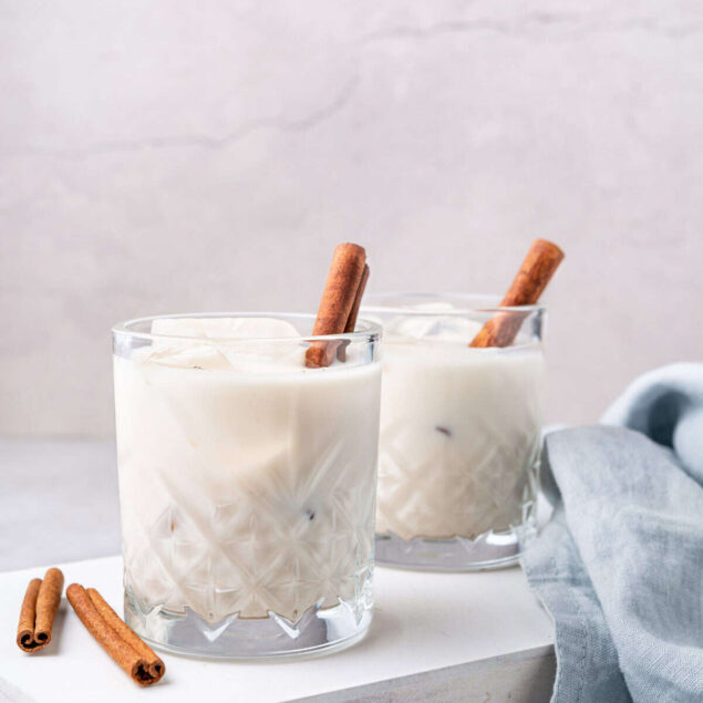 Creamy vanilla spiced iced coffee in elegant glasses garnished with cinnamon sticks, perfect for a nutritious, flavorful beverage from Food Faith Fitness.