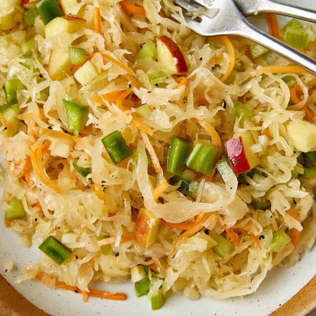 Fresh homemade cabbage slaw with carrots, celery, and apples on a white plate, healthy and nutritious meal option from Food Faith Fitness.