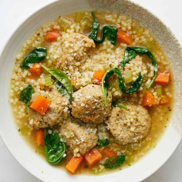Savory chicken and vegetable meatball soup with couscous, carrots, spinach, and herbs in a light broth, perfect for healthy eating and nutritious meal ideas.