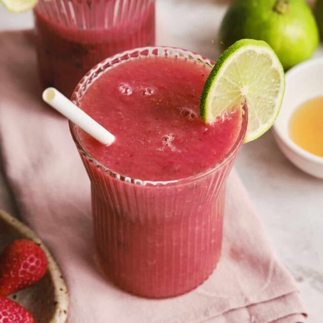 Refreshing strawberry watermelon smoothies garnished with lime wedges, perfect for healthy eating and fitness enthusiasts. Serve in tall glasses with straws, surrounded by fresh fruit and ingredients.