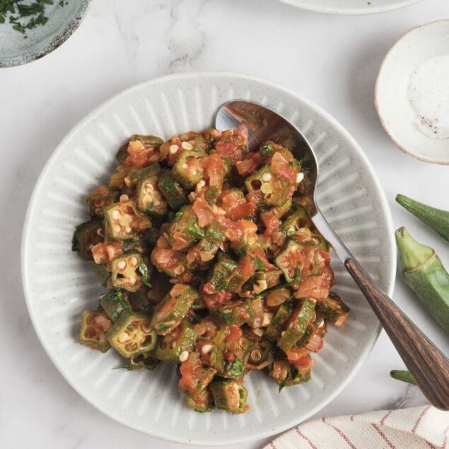 Vegan Okra Tomato Stew on a white plate with fresh okra, lemon, and herbs, healthy gluten-free vegetarian comfort food, perfect for meal prep and nutritious eating.