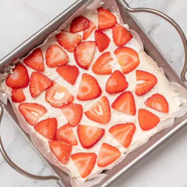 Fresh strawberry layered dessert with whipped cream in a baking dish, healthy fruit dessert recipes, perfect for nutritious snacks or celebrations.