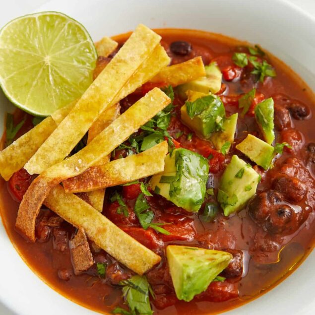 Rich vegetarian chili topped with fresh avocado, crispy fries, and a squeeze of lime, perfect for healthy eating and meal prep. Enjoy a flavorful, nutritious vegan dish.