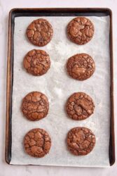Decadent paleo chocolate cookies on a baking sheet with parchment paper, perfect for healthy dessert recipes.